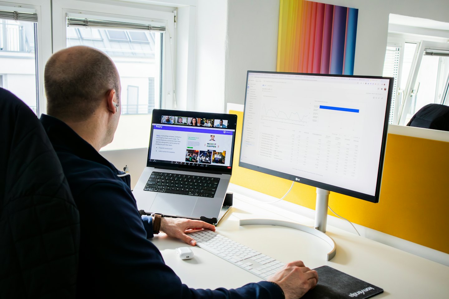 Mężczyzna pracuje na laptopie i monitorze w nowoczesnym biurze.