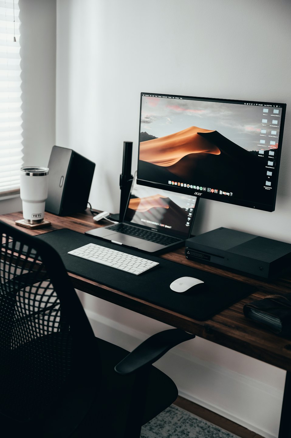 Nowoczesne domowe biuro z laptopem i monitorem na drewnianym biurku.